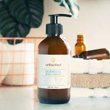 Load image into Gallery viewer, Natural Scented Sea moss BodyCream _ FrontSide _ on top of a bathroom counter with empty bottle in the background of spa